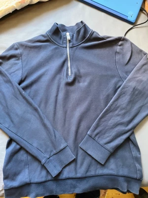 Mörkblå halfzip från Hugo boss - Mörkblå långärmad tröja från hugo boss med halv dragkedja framtill och hög krage. Tröjan har ribbade muddar vid ärmslut och nederkant samt diskreta vita detaljer på insidan av kragen. Perfekt för en clean och stilren look.