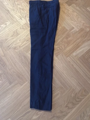 Marinblå linnebyxor dressade - Snygga marinblå linnebyxor från Ralph lauren. Kostymbyxor knäppning. Storleken passar S-M