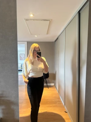 Svarta kostymbyxor med hög midja - Säljer ett par svarta kostymbyxor med hög midja och rak passform. Byxorna har en clean look och är perfekta för en stilren outfit. Materialet är mjukt och följsamt, vilket ger en snygg siluett.