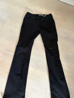 Levi's 715 Bootcut jeans svart - Svarta Levi's 715 Bootcut jeans med klassisk femficksdesign och bootcut passform. Jeansen har dragkedja och knapp framtill samt diskreta detaljer. Perfekt för dig som gillar en tidlös och snygg look.