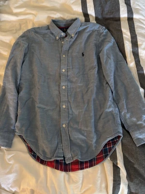 Blå skjorta från Ralph Lauren - Riktigt snygg skjorta från Ralph lauren. Storlek 14-16år så skulle säga XS. Riktigt bra skick, det ända är väl den lilla defekten på bild 3. (Skriv vid funderingar!)