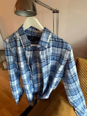 Blårutig skjorta från Ralph Lauren - Blårutit skjorta från Ralph Lauren som passar perfekt nu till sommaren! Perfekt att köra till en vinkväll eller bara en skön dag på stranden! Just denna är 14-16 i large storlek. Alltså skulle denna passa som en Small. Hör av dig vid funderingar. Extremt bra skick Mvh Pelle