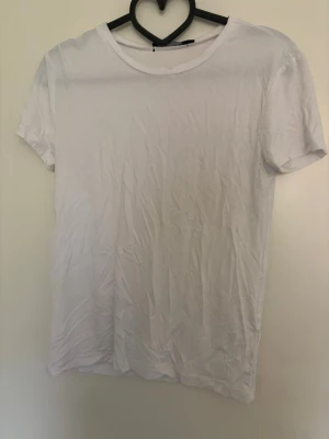 Vit basic t-shirt i bomull - En klassisk vit t-shirt med rund hals och korta ärmar. Tillverkad i mjuk bomull och har en enkel, clean design som passar till det mesta. Perfekt basplagg för garderoben.