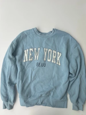Ljusblå sweatshirt New York Gina Tricot - Ljusblå sweatshirt från Gina Tricot. Tröjan har rund halsringning, ribbade muddar vid ärmslut och nederkant samt en avslappnad passform. Perfekt för en chill och trendig look.