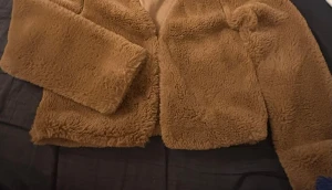 Brun teddy/päls jacka - Mysig brun teddy/pälsjacka med fluffigt material och långa ärmar. Jackan har en enkel design utan synliga knappar eller dragkedja. Passar dig som gillar trendiga och bekväma plagg.