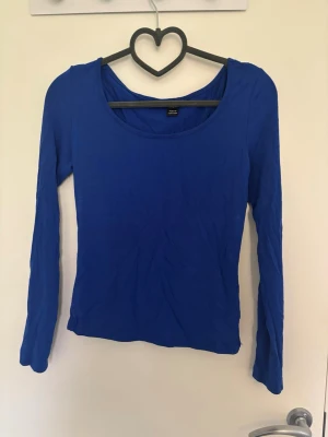 Blå långärmad tajt tröja - En enkel och stilren blå långärmad tajt tröja med rund halsringning. Perfekt att matcha med jeans eller kjol för en clean look. Finns en likadan fast grå i min profil