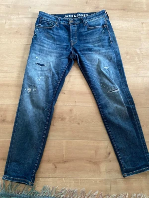 Jack Jones Jeans - Säljer ett par vintage jeans från Jack and Jones. Modellen comfort Mike. Storlek 33/32, skön passform med snygga slitningar. Hör av dig vid intresse. 