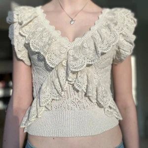 Beige spetsprydd stickad topp - Supersöt beige stickad topp med breda volangdetaljer i spets längs v-ringningen och axlarna. Toppen är ärmlös i storlek S. Priset kan diskuteras 💞