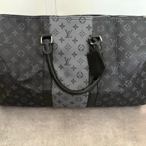 Weekend bag - Weekend bag med mönster på. Grå detalj på en sida, resten helsvart. Justerbar axelrem. Aldrig använd!