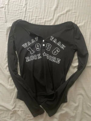 Svart långärmad topp med tryck - Denna är från shein. Svart långärmad topp med vit text framtill. Toppen har knappar vid halsringningen och är figurnära i modellen. Jätte fin på och du kan själv välja hur mycket urringning du vill ha. 