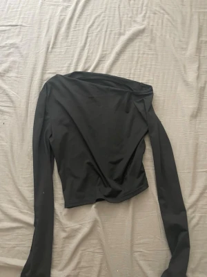 Svart offshoulder långärmad topp - Snygg svart offshoulder topp med långa ärmar och croppad passform. Tillverkad i ett stretchigt syntetmaterial som sitter tight mot kroppen. Från shein därav billiga priset. 