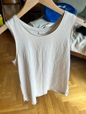 Beige linnetopp från Decathlon - Säljer en enkel och stilren beige linnetopp från Decathlon. Toppen är ärmlös och har en rund halsringning. Perfekt för varma dagar eller som lager under en skjorta. Tillverkad i mjuk bomull för skön känsla.