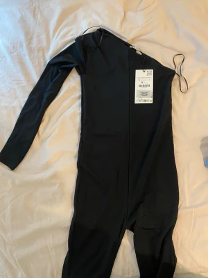 Jumpsuit - Svart tajt jumpsuit med prislapp kvar. Utsvängda i benen. Storlek S men hade passat XS med