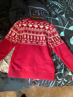Röd jultröja med isbjörnar från H&M - Röd stickad tröja från H&M:s L.O.G.G.-kollektion med vita mönster av isbjörnar, pingviner och snöflingor. Tröjan har rund halsringning, ribbade muddar och klassiskt vintermönster. Perfekt för vintersäsongen och julmys. Priset är inte huggit i sten och jag tar gärna emot prisförslag.