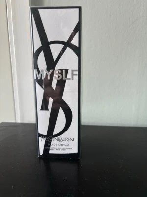Yves Saint Laurent MYSLF Eau de Parfum - Säljer en elegant parfym från Yves Saint Laurent, MYSLF Eau de Parfum. Förpackningen är svartvit med stor YSL-logga och modern design. Parfymen kommer i en stilren rektangulär kartong och är en påfyllningsbar spray. Perfekt för dig som gillar exklusiva dofter.