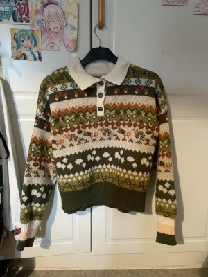 Mönstrad stickad tröja med krage - Säljer en stickad tröja med retroinspirerat mönster i grönt, beige, orange och vitt. Tröjan har en bred krage, tre knappar framtill och ribbstickade muddar. Perfekt för dig som gillar unika och mysiga plagg med vintagekänsla. Köpt från koreanska märket DAZY för 239kr, säljer för 150kr. Använd fåtal gånger utan defekter. Asiatisk storlek XL, EU L