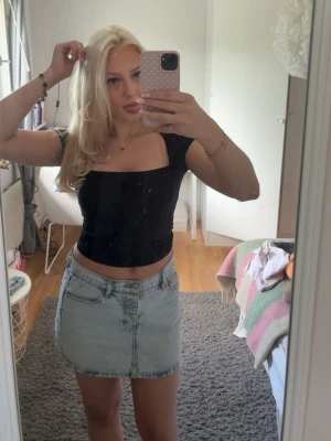 Svart croppad topp med fyrkantig ringning - Trendig svart croppad topp med fyrkantig ringning och korta ärmar. Sitter tight och är perfekt att matcha med kjol eller jeans. Enkel och stilren design som passar till många olika looks. Användt 2 gånger. ❤️