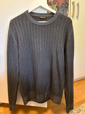 Mörkgrå ribbstickad tröja - Snygg mörkgrå ribbstickad tröja från Stenströms med rund halsringning och långa ärmar. Tröjan har en klassisk passform och är tillverkad i ett mjukt stickat material som passar perfekt till jeans eller chinos.