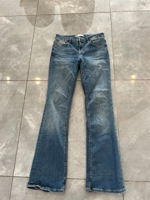 Blå bootcut jeans från ZARA - Säljer ett par blå bootcut jeans från ZARA med klassisk femficksdesign och snygga slitningar. Jeansen har normal midja och är tillverkade i denim med lätt stretch. Perfekta för dig som gillar en avslappnad men trendig look.