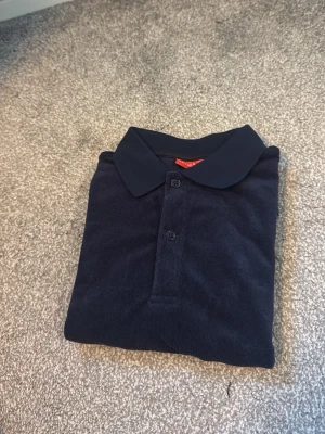 RYVLS pike  - Klassisk mörkblå pikétröja från STYLS med krage och två knappar framtill. Tillverkad i mjukt material som känns bekvämt mot huden. Perfekt till jeans eller shorts för en enkel och stilren look.
