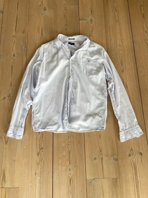 Ljusblå skjorta från Gant - Skjortan har lång ärm och en stilren krage, perfekt för en clean och tidlös look. Storlek: för personer runt 170 cm/15 år