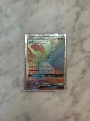 Charizard GX Pokémonkort Rainbow Rare - OBS KAN SKRIVA FÖRSLAG PÅ PRIS, HÖGST BUD FÅR KORTET             Säljer ett Charizard GX Rainbow Rare Pokémonkort med holografisk yta. Kortet har färgstark regnbågseffekt och visar Charizard med attacker som Wing Attack, Crimson Storm och Raging Out GX. Perfekt för samlare eller Pokémonfans. Dom säljs inte längre och är jätte jätte sällsynta , perfekt för er som samlar på kort.