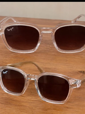 Haga transparenta solglasögon - Snygga solglasögon från Haga med transparent plastbåge och bruna tonade glas. Klassisk fyrkantig form som ger en modern vibe. Perfekta för att lyfta din stil under soliga dagar.Priset går att diskuteras.