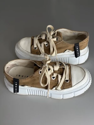 Inuikii Skor - Snygga beige sneakers från Inuikii med vit tjock sula och tåparti i vitt gummi. Skorna har beige textilovandel, vita skosnören och svarta detaljer med logga på hälen. Nypris : ca 2400 SEK Pris : 600 SEK