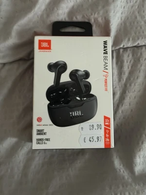JBL Wave Beam True Wireless Svart - Säljer ett par svarta JBL Wave Beam True Wireless in-ear hörlurar med laddningsetui. Hörlurarna har smart ambient-funktion och är perfekta för handsfree-samtal. Snygg och modern design med JBL-logga på både hörlurar och etui.