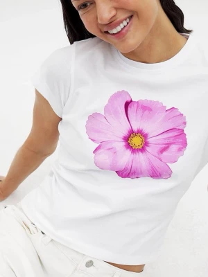 Vit t-shirt med rosa blomma - Snygg vit t-shirt med en stor rosa blomma tryckt framtill. T-shirten har korta ärmar och en klassisk rund halsringning. Perfekt för dig som vill ha en enkel men ändå färgstark look. Tillverkad i mjuk bomull för skön känsla hela dagen.