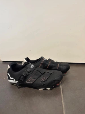 Svarta cykelskor från Northwave strl 37 - Säljer ett par svarta cykelskor från Northwave med vita detaljer och spänne för extra bra passform. Skorna har kardborreband. Storlek 37.