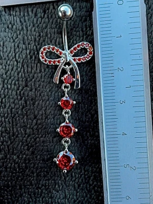 NY oanvänd Navelpiercing med hänge | Kirurgiskt stål | Rosett och röda stenar  - 💕30% Bundle-rabatt vid köp av minst 2 artiklar. ⭐️NY oanvänd piercing i kirurgiskt stål; rostfritt och säkert för läkta piercingar.                               📏MÅTT ⭕️Stavens längd: 10mm ⭕️Stavens tjocklek: 1,6mm ⭕️Smyckets totala längd: 50mm                                                                         🤍Färger: Silver och röd                                                          💌Skickas spårbart via Plick SafePay.