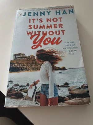 It's Not Summer Without You av Jenny Han - En ungdomsroman på engelska av Jenny Han. Omslaget är ljust med en strandbild och en tjej i shorts och vit blus. Boken handlar om kärlek, vänskap och svåra val under sommaren. Perfekt för dig som gillar romantik och coming-of-age berättelser.