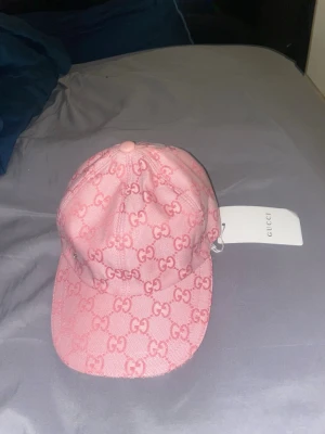Guccl keps rosa - Snygg rosa keps från guccl med klassiskt -monogram över hela kepsen. Justerbar rem baktill och böjd skärm. Tillverkad i canvasmaterial med ljus insida. Perfekt accessoar för att lyfta din streetwear-look.