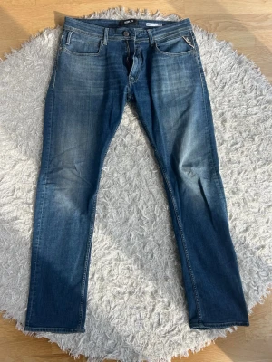 Replay Jeans - Snygga blå slim fit jeans från Replay med klassisk femficksdesign och diskreta slitningar framtill. Modellen heter Dave. Jeansen har normal midja och raka ben, tillverkade i stretchigt denim för extra komfort. Perfekta för en trendig och avslappnad look. Har nästan bara legat i min garderob senaste året, är i väldigt bra skick