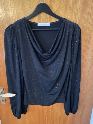 Svart glittrig blus från Sisters Point - Supersnygg elegant, svart glittrig topp/blus från sister point. Använd 1 gång så den är i toppskick. Passar till vardags och som festtopp