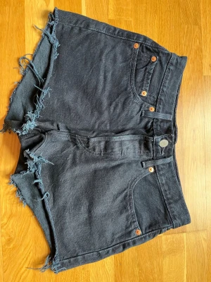 Levis 501 jeansshorts - Jeansshorts från Levis, modell 501. Strl 26. Midjemått tvärsöver ca 34 cm enligt bild. Shortsen är lite mer blåsvarta än vad de ser ut på bilderna. 