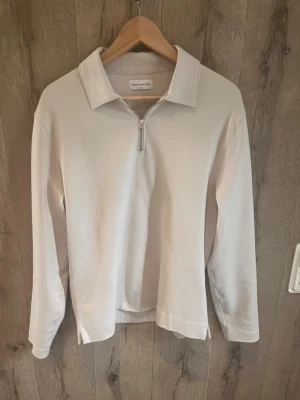 Beige ziptröja från These Glory Days - Stilren beige ziptröja från These Glory Days med halv dragkedja och klassisk krage. Tröjan har långa ärmar och är gjord i mjukt bomullsmaterial. Perfekt för en avslappnad och trendig look.