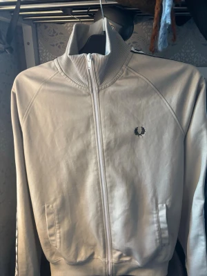 Beige zip hoodie från Fred Perry - Snygg beige zip hoodie från Fred Perry, säljer för att jag växt ut den! Nypris 1399! Mitt pris 600