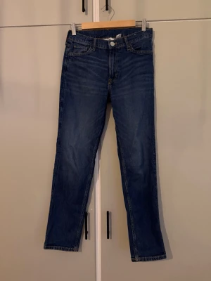 Mörkblå slim fit jeans från H&M - Snygga mörkblå slim fit jeans från H&M med justerbar midja. Klassisk femficksmodell och raka ben. Ca 90cm.