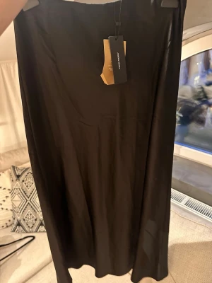 Svart satin långkjol från Vero Moda - Satinlkjol från Vero Moda i ett mjukt och glansigt material. Kjolen har en enkel och rak passform och är i storlek M. Aldrig använd med prislapp kvar