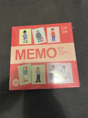 Memo-spel Elsa & Sam yrken - Ett memo-spel med yrken från Elsa & Sam. Spelet kommer i en fyrkantig röd och beige kartong med illustrationer av olika yrkespersoner på framsidan. Passar barn från 3 år och uppåt. Perfekt för att lära sig om olika yrken på ett roligt sätt.