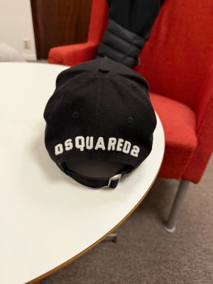Svart keps från DSQUARED2 - Snygg svart keps från DSQUARED2 med broderad logga på insidan. Klassisk böjd skärm och justerbar passform. Tillverkad i bomull och designad med märkets ikoniska stil. Perfekt accessoar för en trendig look.