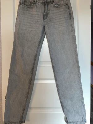 Grå raka jeans från Gina Tricot - Säljer ett par ljusgrå jeans från Gina Tricot i modellen Perfect flare. Jeansen har raka, vida ben och klassisk femficksdesign med bälteshällor. Materialet är denim i bomull och de har knapp- och dragkedjegylf. Perfekta för en avslappnad och trendig look.