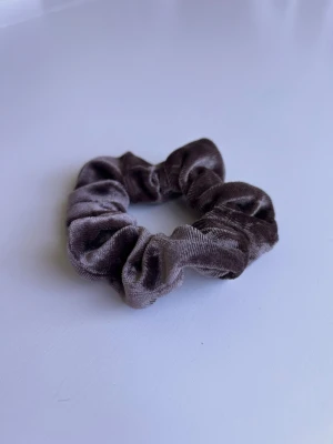Brun schrunchie - En liten brun scrunchie. Knappt blivit använd!