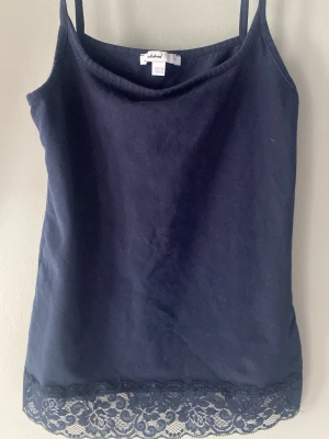 Marinblå linne med spets från Subded  - Gulligt marinblått linne från Subded med tunna axelband och dekorativ spetskant nertill. Perfekt att styla till jeans eller kjol. Tillverkat i mjukt material som känns skönt mot huden. Fick i julklapp och har tyvärr inte kommit till användning. Köp gärna. 25 % går till Cancerfonden ❤️