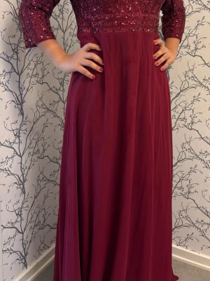Vinröd långklänning med paljetter s-xl - (Stl L men passar stl S upp) Elegant vinröd långklänning med paljetter upptill och trekvartsärm. Klänningen har en flytande kjol i mjukt tyg och en markerad midja. Perfekt för speciella tillfällen och ger en lyxig känsla.