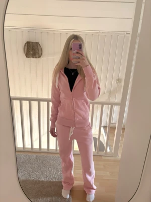 Rosa hoodie med dragkedja från Russemerch - Ljusrosa hoodie från Russemerch med dragkedja, huva och fickor framtill. Tillverkad i mjukt, fleeceliknande material på insidan för extra komfort. Perfekt för en avslappnad och trendig look.