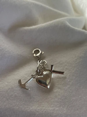 Berlock i äkta silver  - Berlock i äkta silver i form av ett ankare, hjärta och kors från Mood. Kan sättas på armband eller halsband. Perfekt för Zara Larsson vibe.  Har flera berlocker som säljs som kan köpas via bundle.
