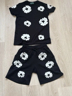 Svart set med vita blommönster - Säljer ett svart tvådelat set med t-shirt och shorts